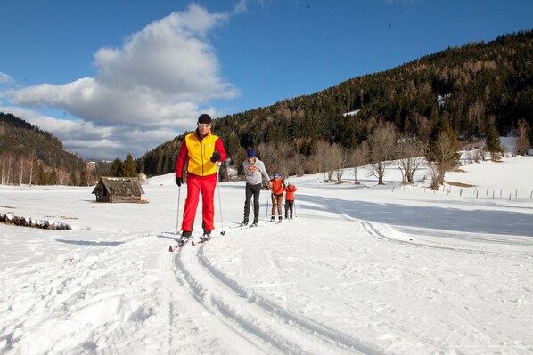 A snowy landscape with a wooden cabin and a group of people skiing.