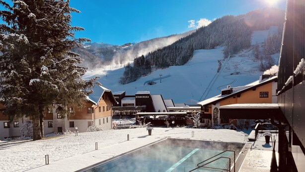 Zona de piscina exterior cubierta de nieve, con vista despejada a una montaña al fondo.