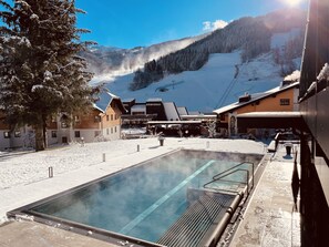 Zona de piscina exterior cubierta de nieve, con vista despejada a una montaña al fondo.