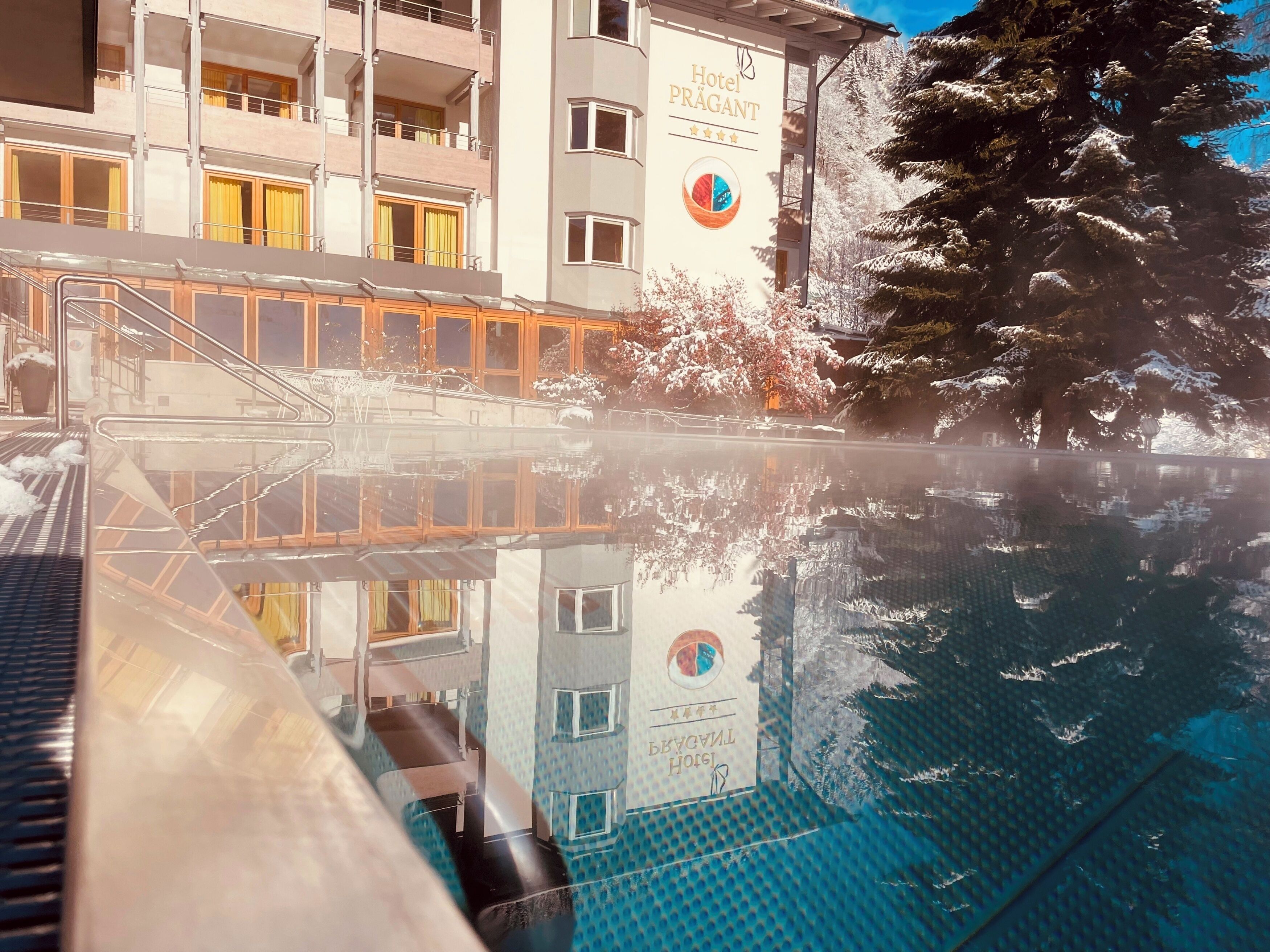 A hotel building with a reflection in a pool. The hotel has multiple floors with balconies.