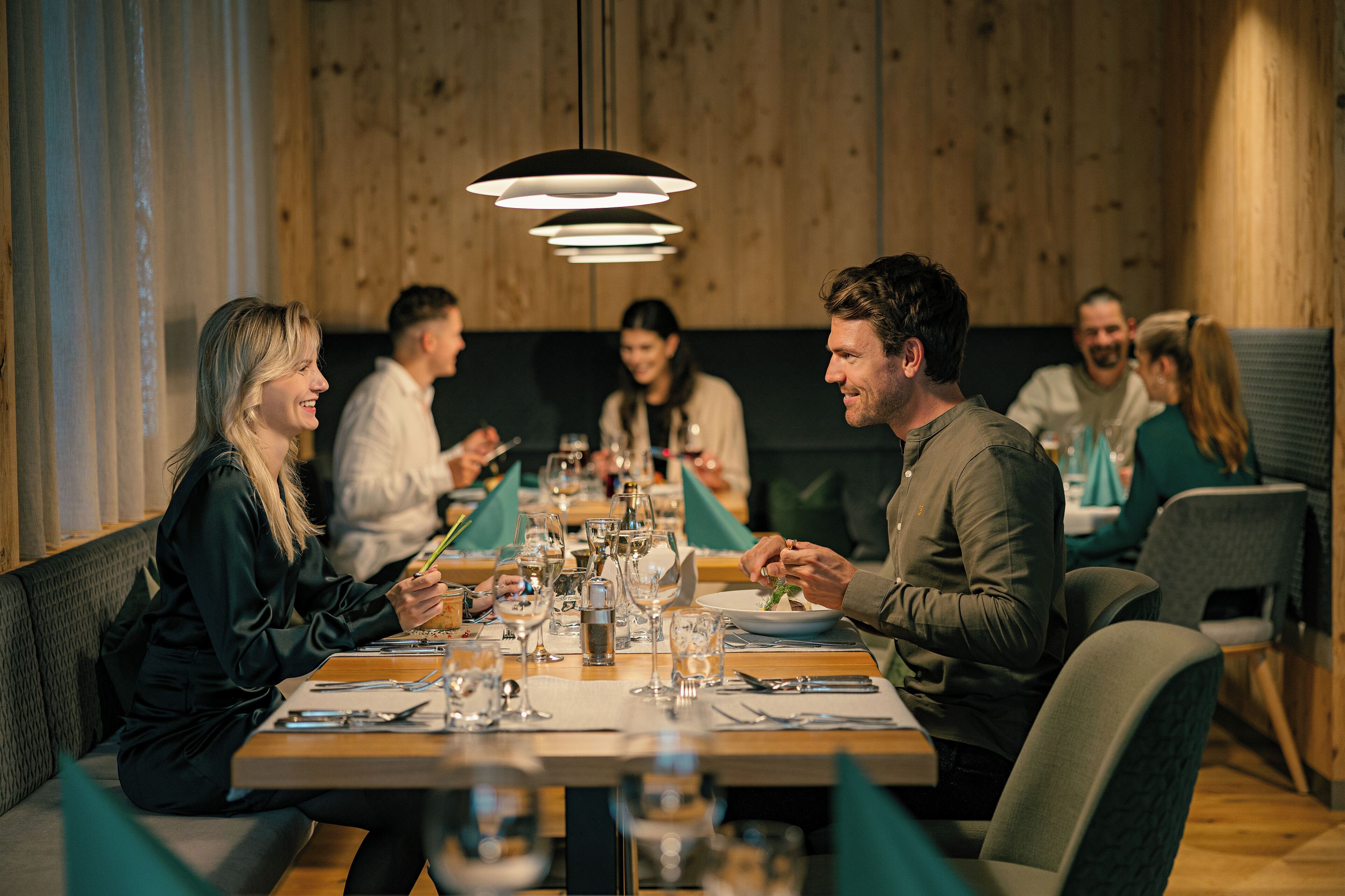 Un grupo de personas cenando en un restaurante con interiores de madera y mesas dispuestas para comidas.