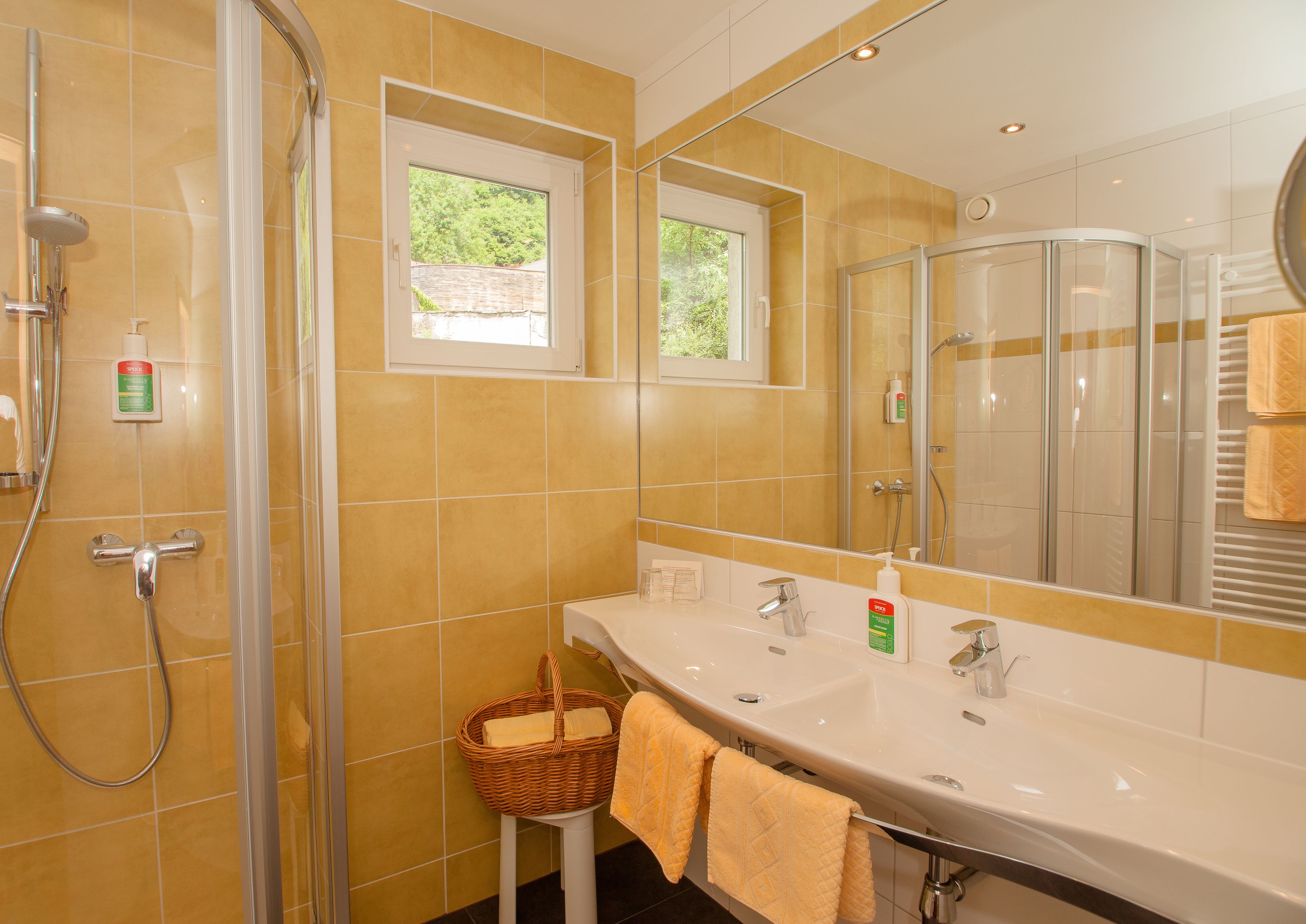 A bathroom with a shower, a sink with a mirror, and a window.