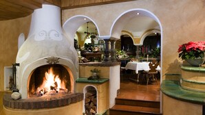 Un interior acogedor con chimenea, vigas de madera y una zona de comedor con mesa y sillas.