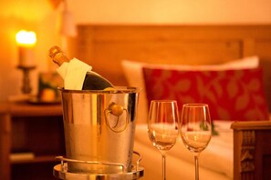 A metallic champagne bucket with a bottle, two empty wine glasses, and a candle on a table in a warmly lit room. - Lutherhotel Eisenacher Hof - Ringhotel (Eisenach)