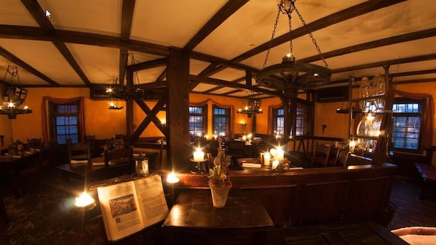 A dimly lit restaurant with wooden beams and hanging lanterns, tables with candles, and a menu on the table. - Lutherhotel Eisenacher Hof - Ringhotel (Eisenach)