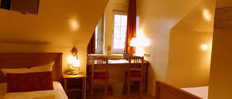 A hotel room with a bed, a desk, two chairs, and a window.
