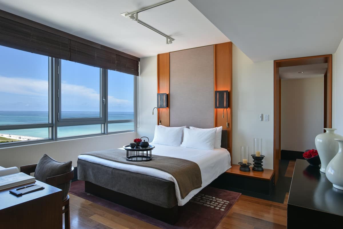 Ein modernes Hotelzimmer mit einem großen Bett, einem Schreibtisch und Blick auf den Ozean.