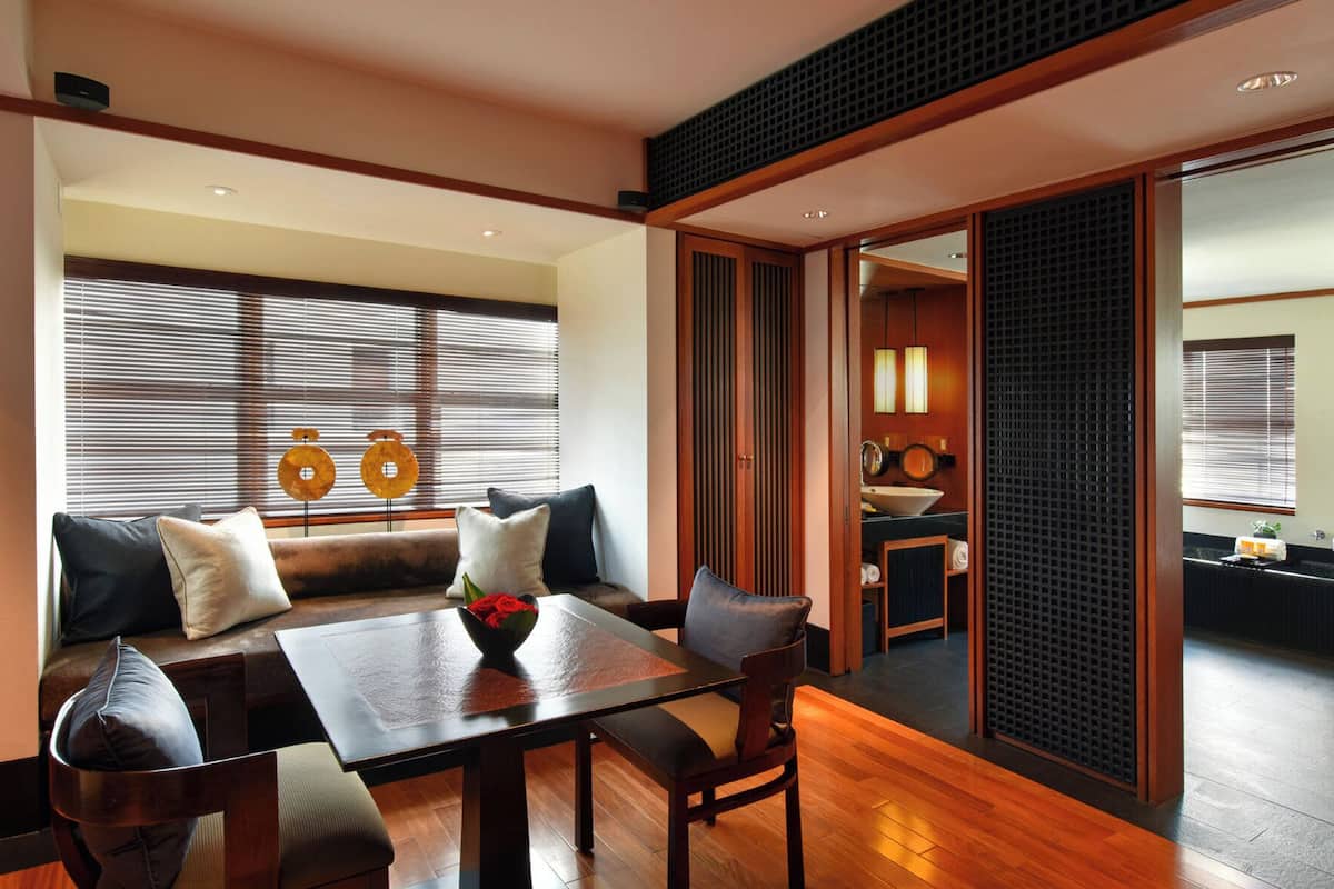 Ein traditioneller japanischer Raum mit Sitzgelegenheit auf Tatami-Matten, einem Holztisch und einer Schiebetür zum Badezimmer.