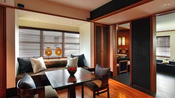 Una habitación de estilo japonés tradicional con zona de estar con esteras de tatami, una mesa de comedor de madera y una puerta corredera que da al baño.