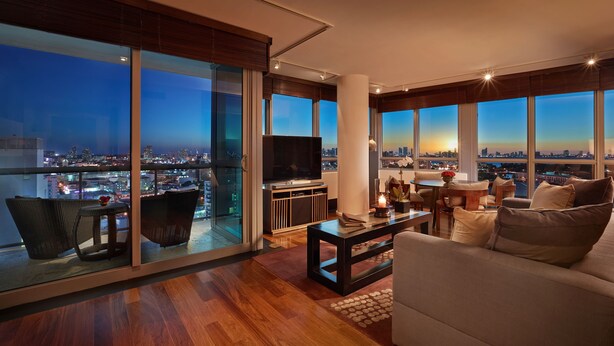 A modern living room with a city view, a flat-screen TV, and a cozy seating area.