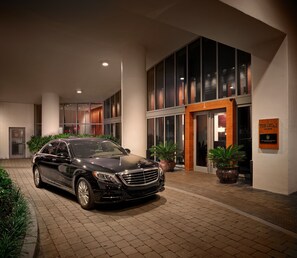 A black car parked in front of a hotel entrance with a sign reading "The Setai".