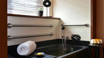 A bathroom with a black sink, towel rack, and a small potted plant on the window sill.