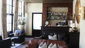 Ein modernes Wohnzimmer mit Ledermöbeln, einem Couchtisch und einer Bar mit verschiedenen Flaschen.