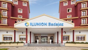A hotel entrance with a red facade, a white central section, and the name "ILUNION Badajoz" prominently displayed. - Hotel ILUNION Golf Badajoz (Badajoz)