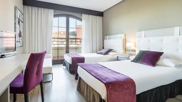 Habitación de hotel con dos camas, un escritorio y un televisor.