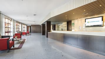 Vestíbulo de hotel con una recepción, zona de estar y ventanas amplias.