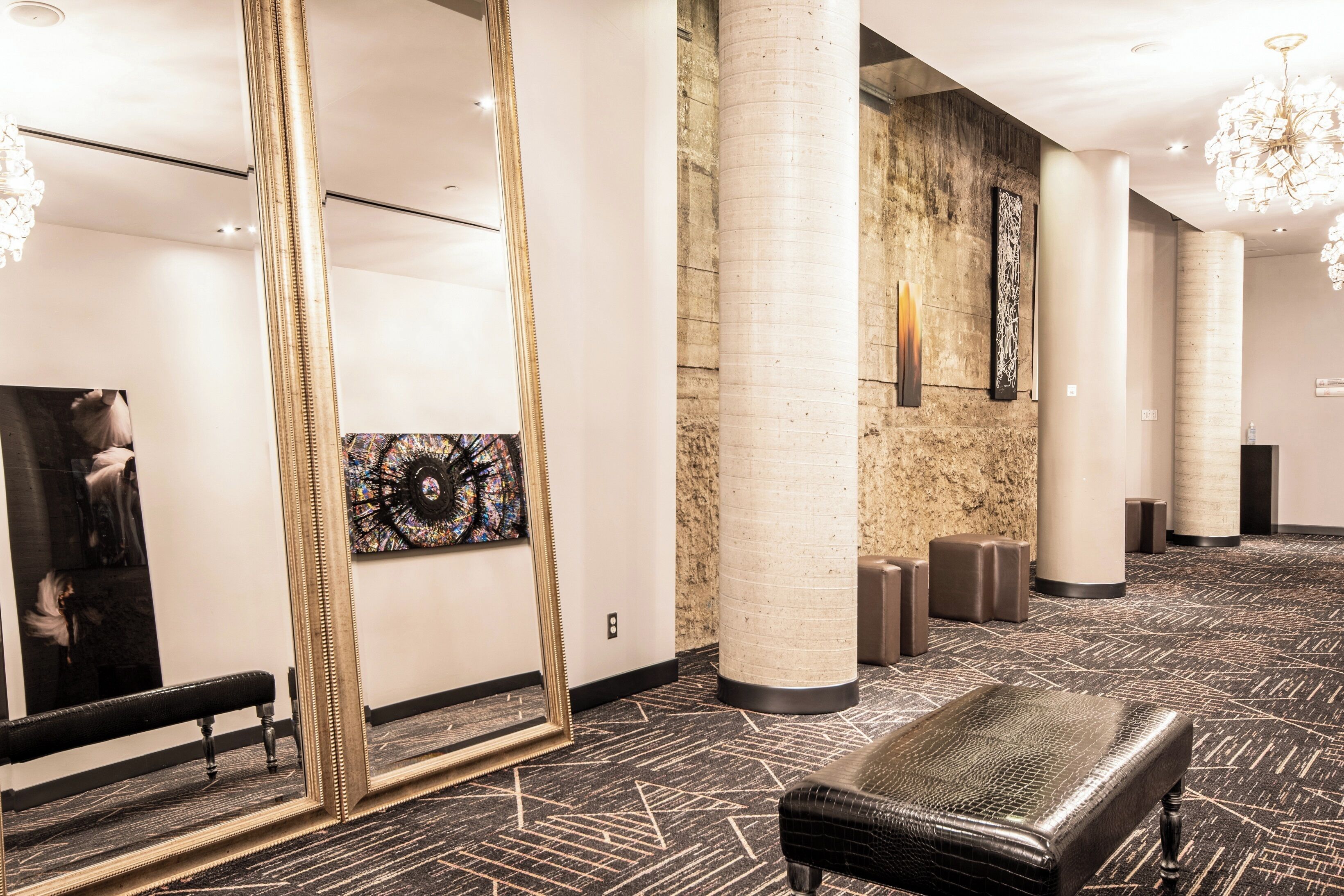A spacious lobby with a large mirror, a bench, and a modern chandelier.