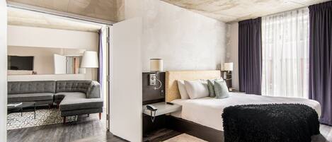 Una habitación de hotel moderna con una cama grande, un sofá y un escritorio.