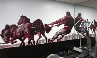 Un gimnasio con un gran mural de un hombre tirando de un caballo, equipo de ejercicio y una cinta de correr.