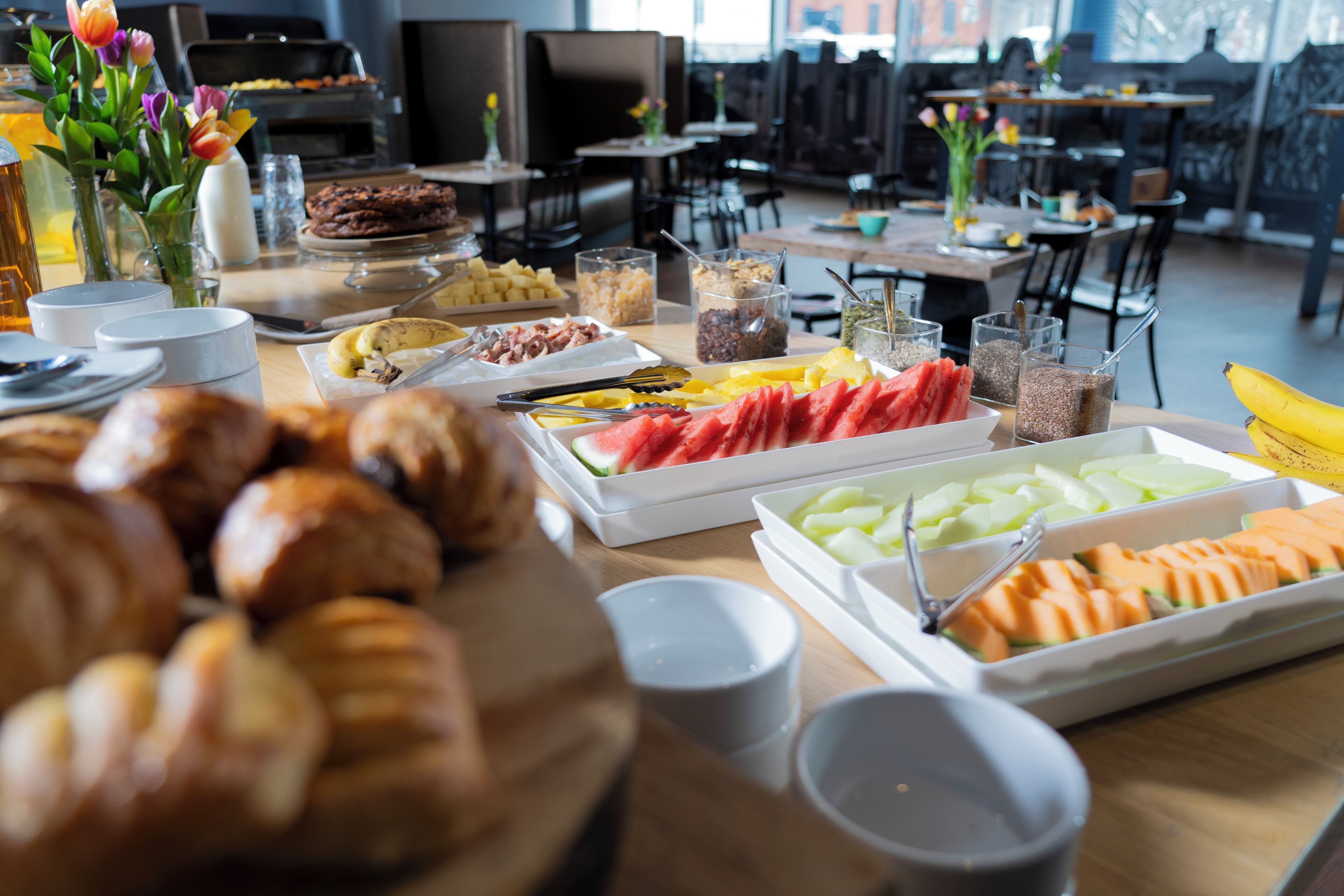 Un bufé con distintos tipos de comida, incluyendo pasteles, frutas y un pastel de chocolate.