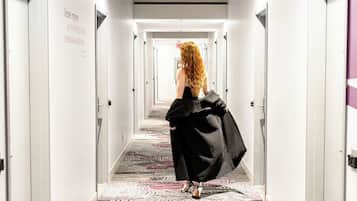 A hotel hallway with a patterned carpet, white walls, and doors on both sides.