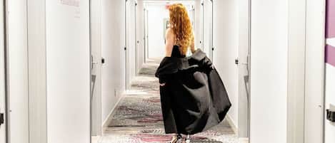 A hotel hallway with a patterned carpet, white walls, and doors on both sides.