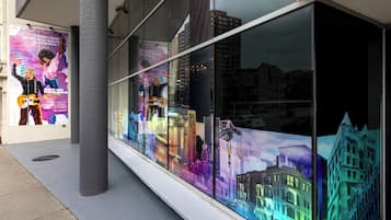 Eine Gebäudefassade mit großen Fenstern, die farbenfrohe Kunstwerke zeigen.