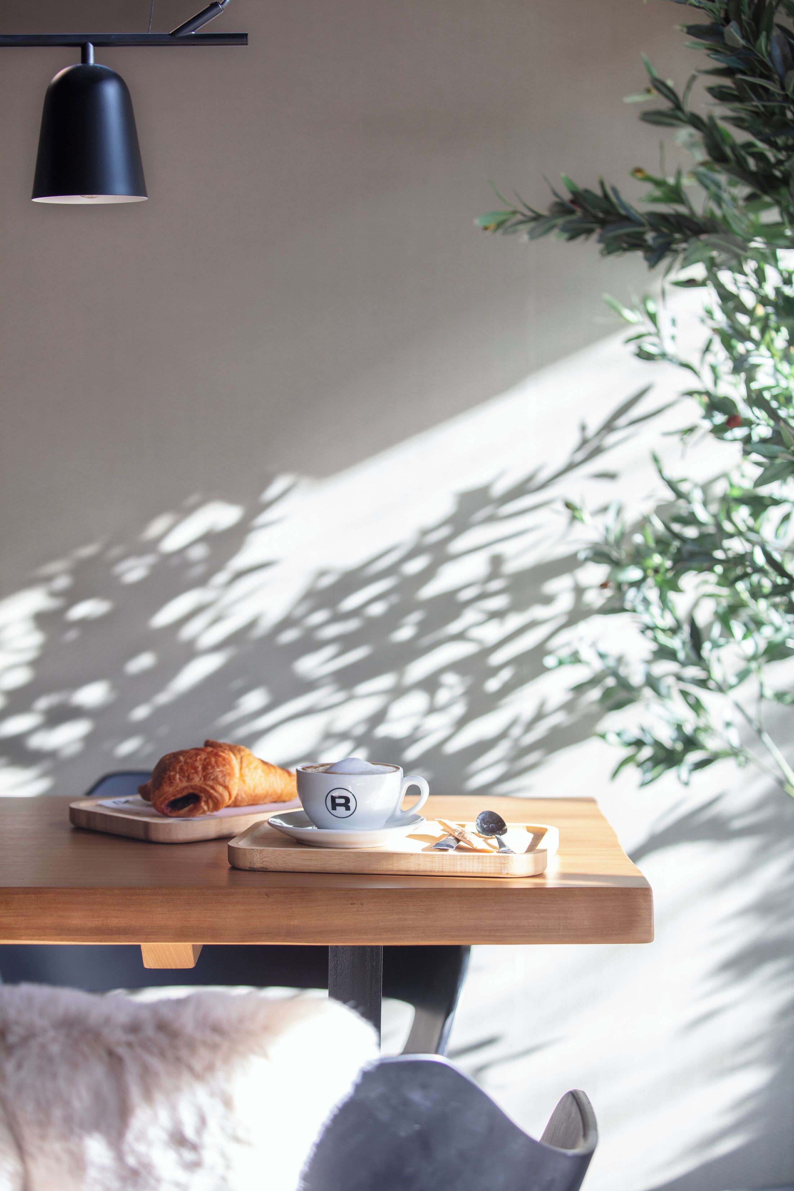 Ett frukostbord med en croissant, en kopp och en tallrik.