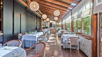 Un restaurante con vigas de madera, luces colgantes redondas y mesas dispuestas para comer.