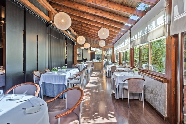 A restaurant with wooden beams, round hanging lights, and tables set for dining. - Hotel Acta Arthotel (Andorra la Vella)