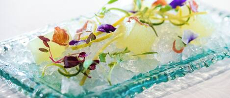 Un recipiente de vidrio con una ensalada colorida sobre una cama de hielo.