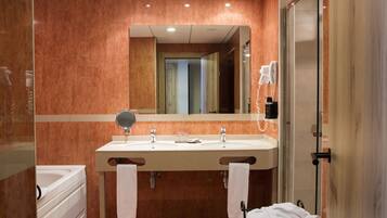 A modern bathroom with a double sink, a mirror, a hairdryer, and a shower.