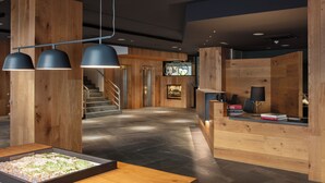 Un área de recepción moderna con detalles de madera, un mostrador de recepción y una escalera que conduce a un piso superior.