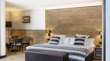 Una habitación de hotel moderna con una cama grande, un escritorio con sillas y una pared de detalles en madera.