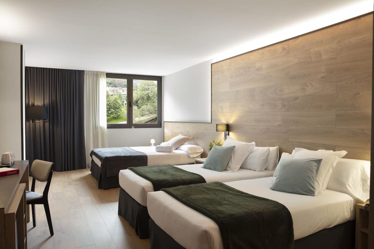 A hotel room with two single beds, a desk, and a chair.