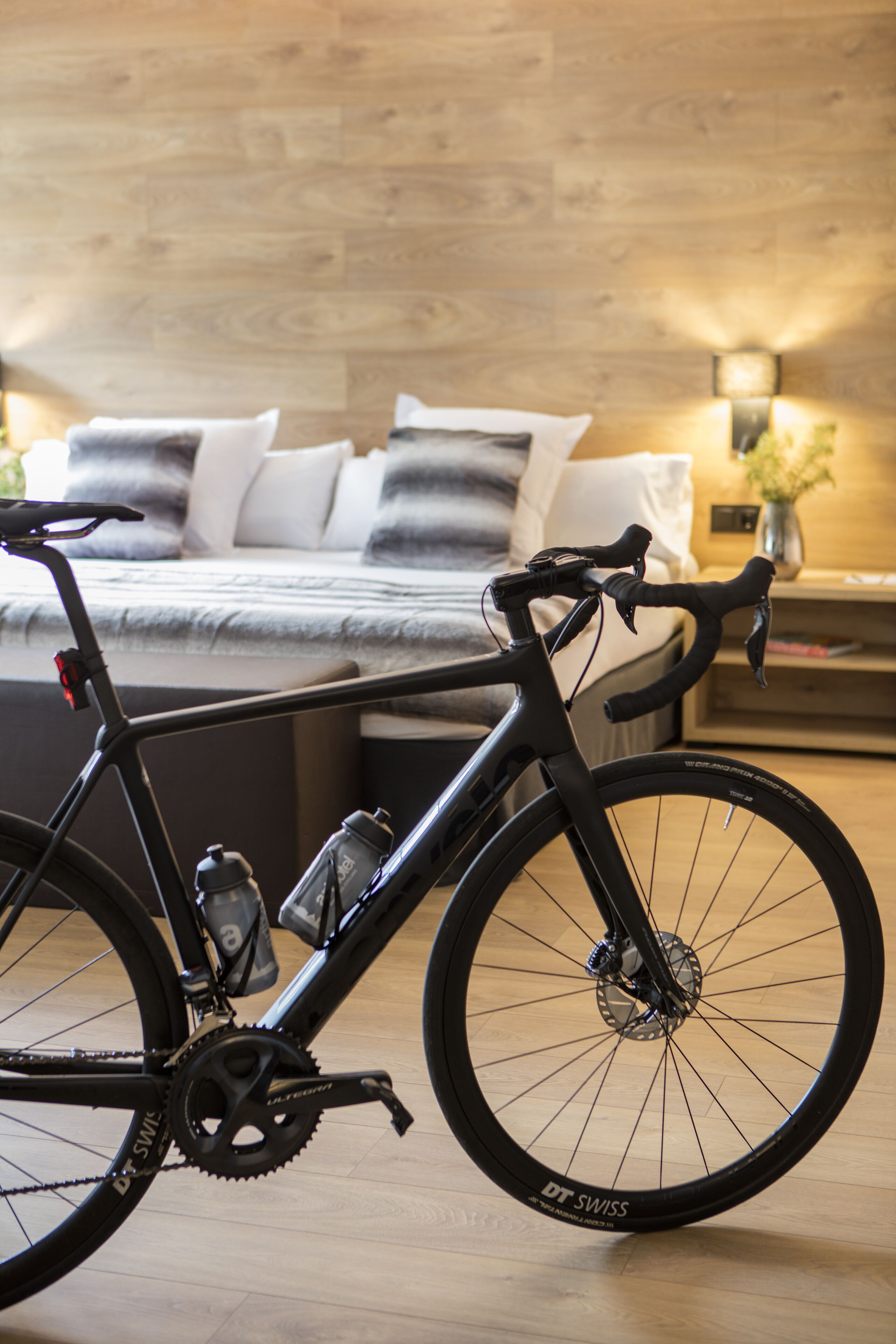 A modern bedroom with a bed, a bedside table, and a bicycle in the foreground.