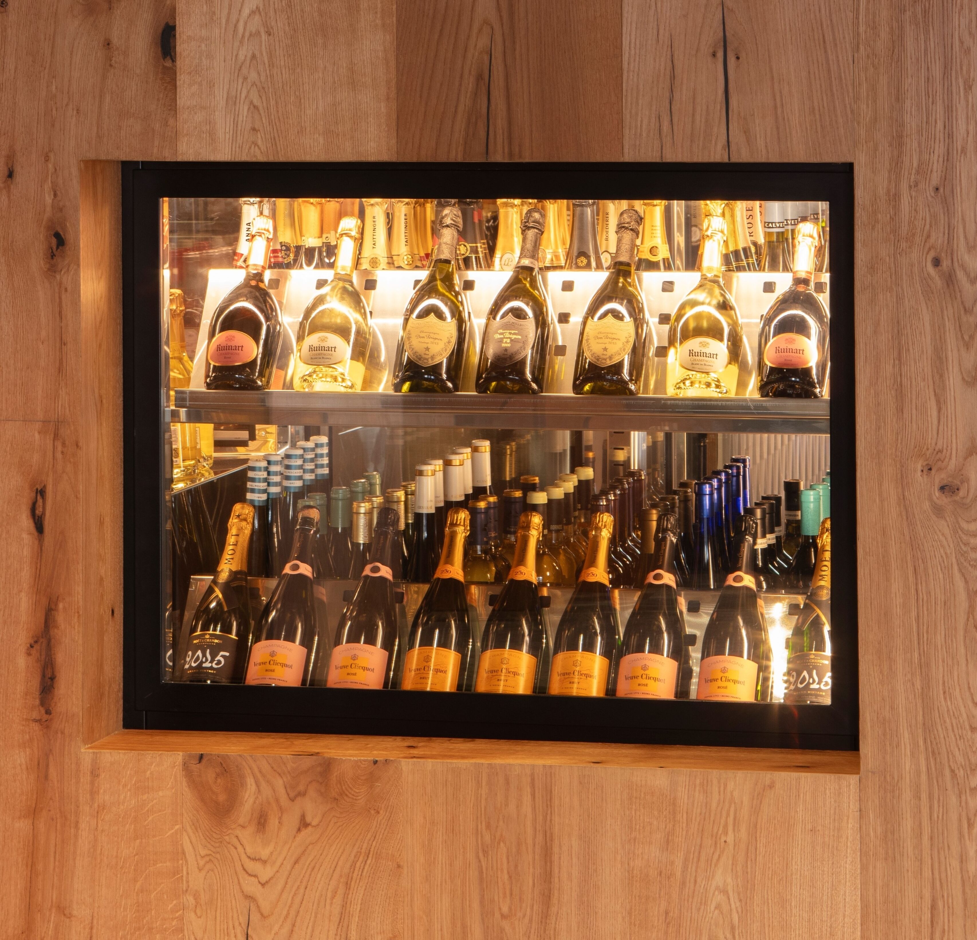 A wine display case with various bottles of Ruinart and Veuve Clicquot champagne.