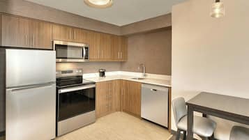 A modern kitchen with stainless steel appliances, wooden cabinets, and a dining area with a table and chairs.