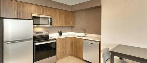 A modern kitchen with stainless steel appliances, wooden cabinets, and a dining area with a table and chairs.