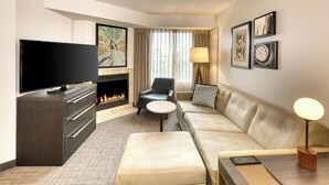 A modern hotel room with a flat-screen TV, a fireplace, a sofa, a coffee table, and a lamp. - Residence Inn by Marriott Whitby (Whitby)