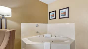 A modern bathroom with a large bathtub, a towel rack, and two framed pictures on the wall.