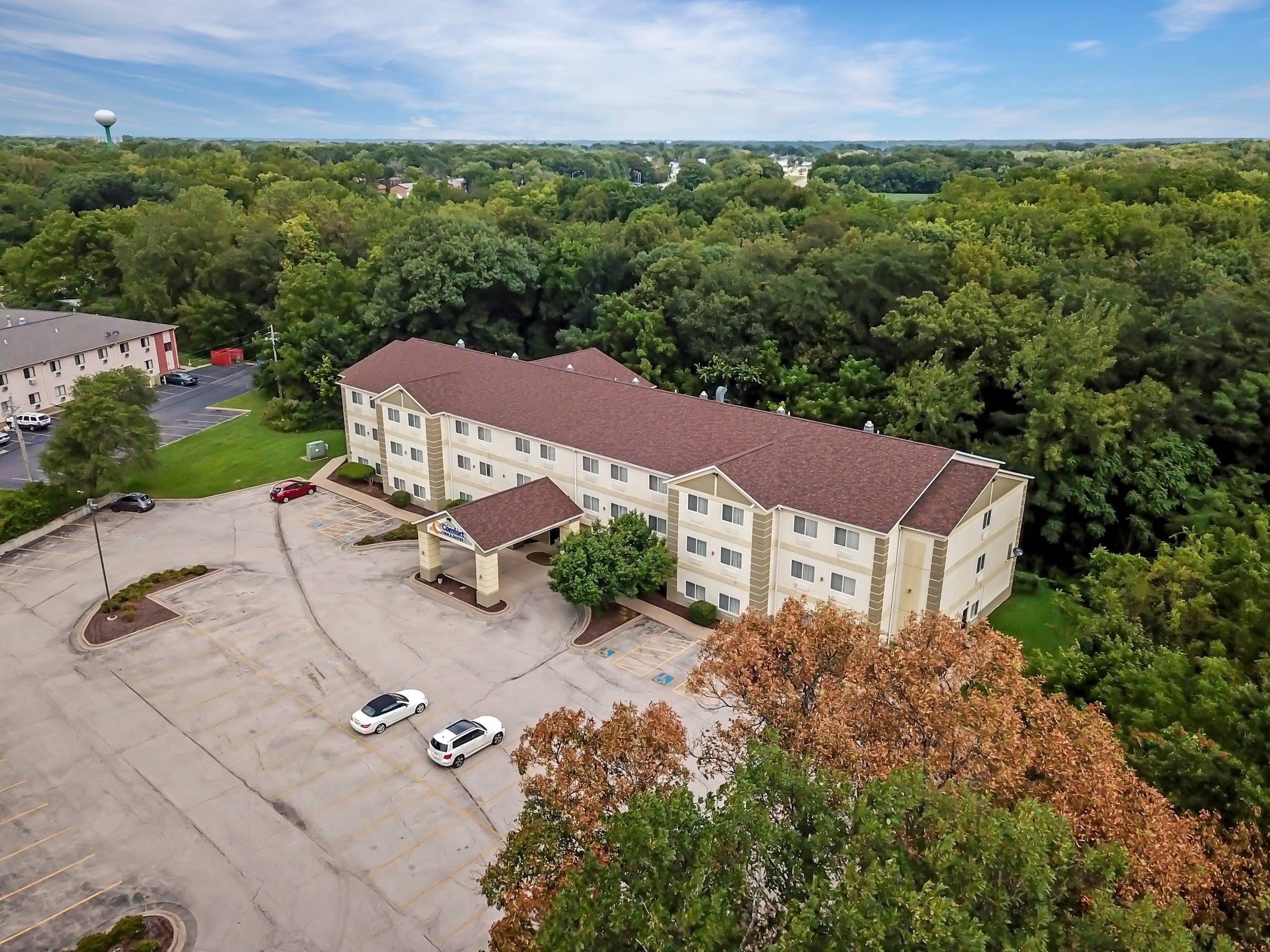 A multi-story hotel with a parking lot and a large green lawn in front.