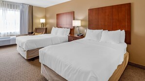 A hotel room with two beds, a chair, a nightstand with a lamp, and a window with curtains.
