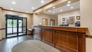A reception area with a wooden reception desk, a glass door entrance, and a small reception desk with a computer.