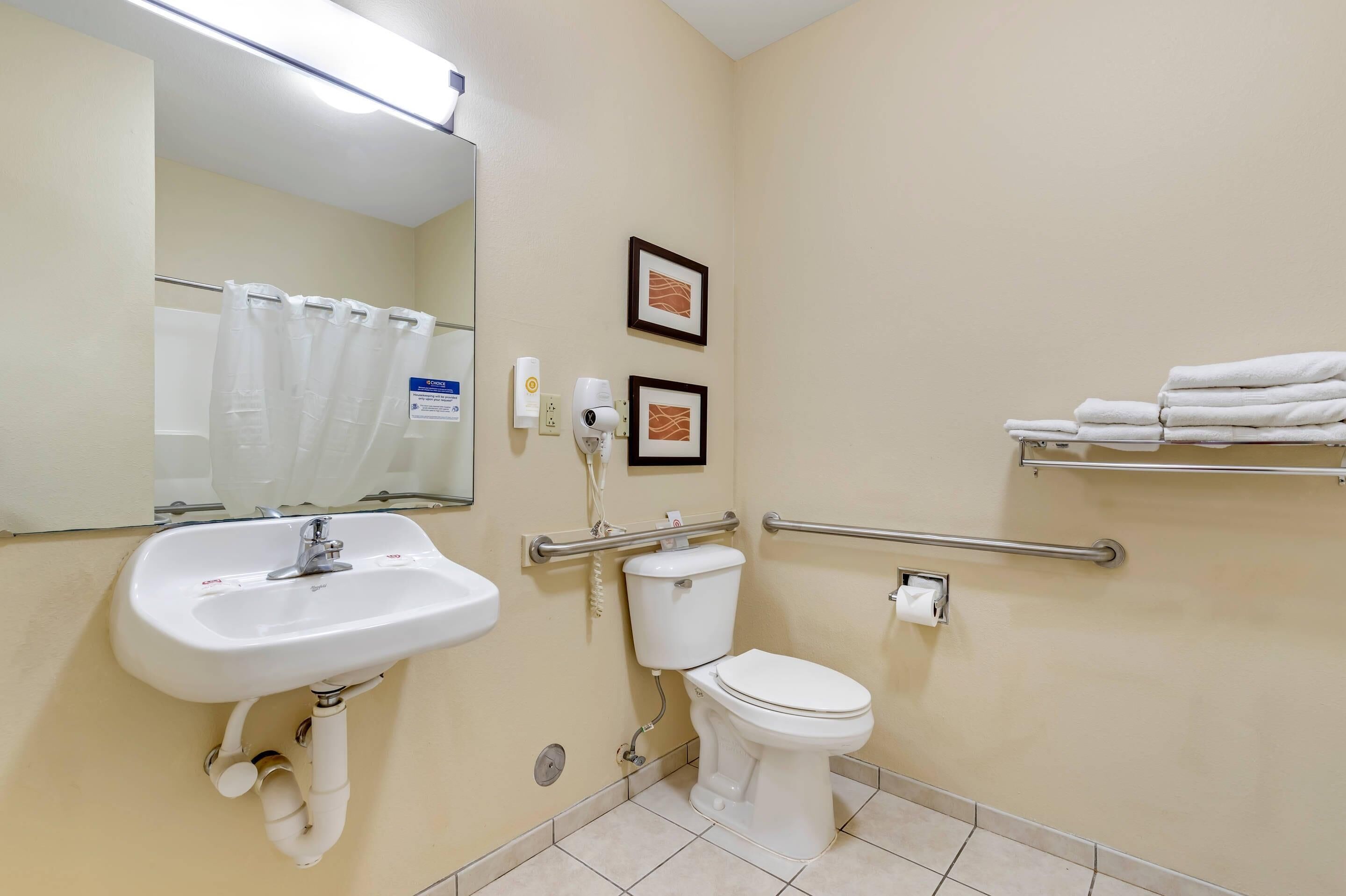 A bathroom with a sink, toilet, hand dryer, and towel rack.