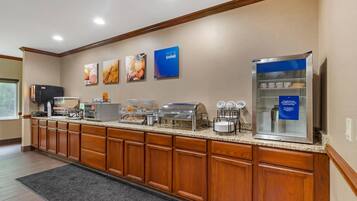 Cozinha de hotel com buffet, incluindo frigorífico, micro-ondas e diversas opções de comida.