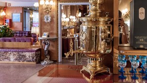 A luxurious lobby with ornate decor, including a large brass stove, elegant furniture, and a display of blue glassware. - Hotel Venezia (Mestre)