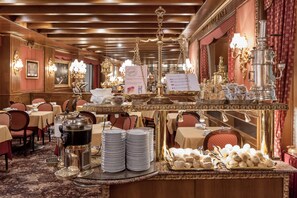 A buffet setup with multiple serving stations, including a coffee machine, stacked plates, and a tray of pastries. - Hotel Venezia (Mestre)