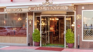 The exterior of Hotel Venezuela, featuring a classic design with a prominent entrance, two potted plants, and a visible car parked outside. - Hotel Venezia (Mestre)