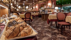 A restaurant with tables and chairs, a buffet with pastries, and a chandelier. - Hotel Venezia (Mestre)